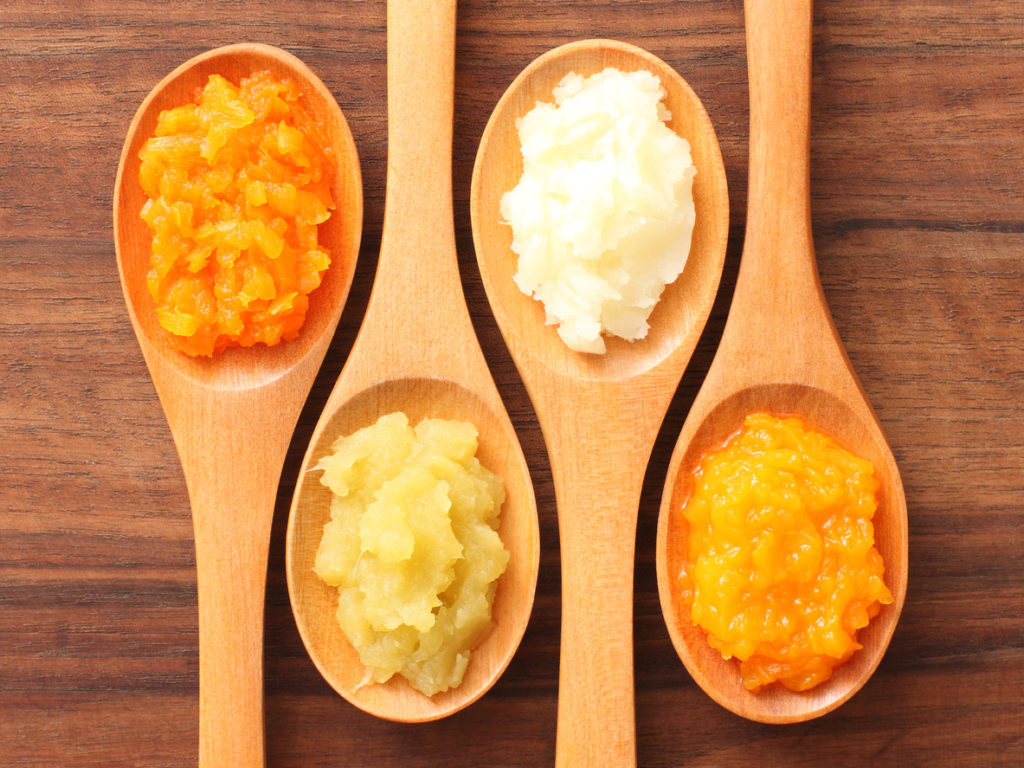 Four spoons with purees on them. From left to right: carrot, sweet potato, potato, squash